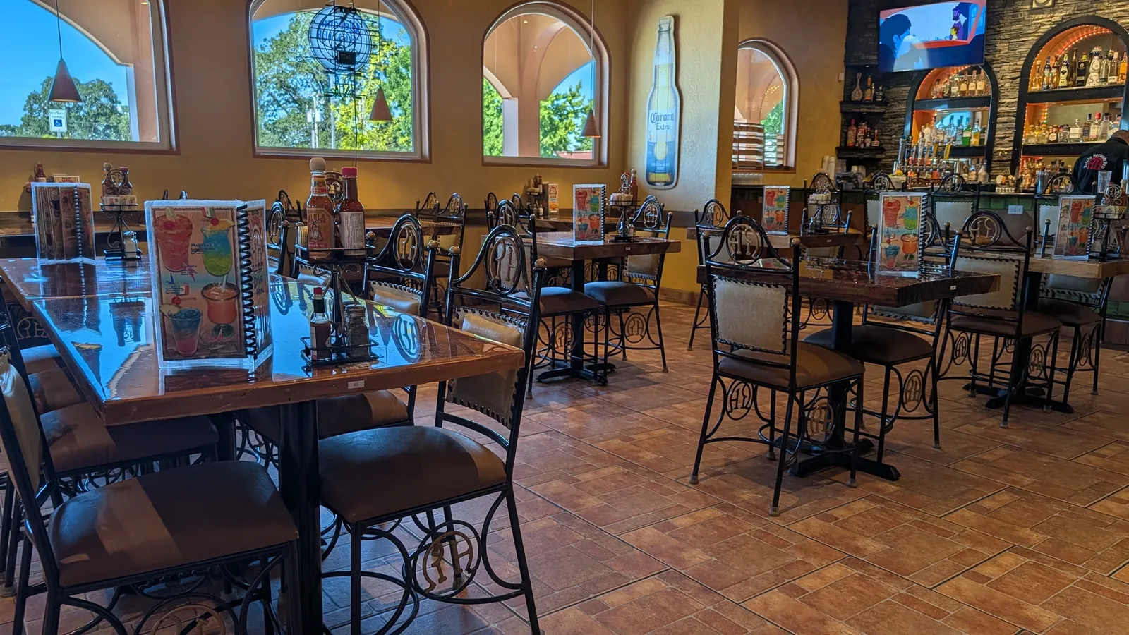 The dining room: arched windows, wrought-iron chairs, tile floor and the bar