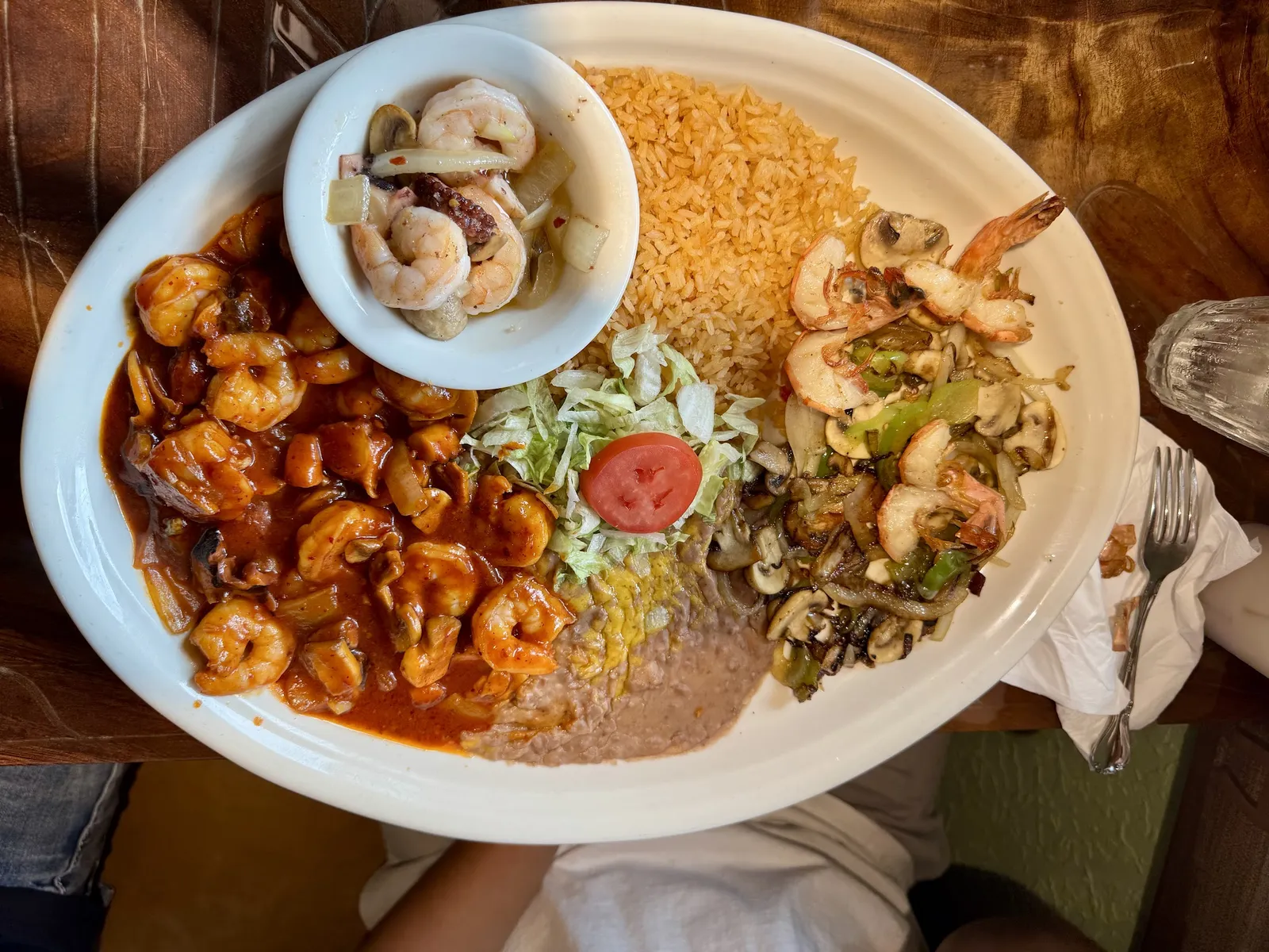 Shrimp in a glossy red chile sauce with rice, avocado and lime